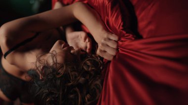 Yatakta saten çarşaf sıkan şehvetli kadın. Yatakta yatan seksi vücut kızı..