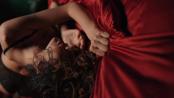 Yatakta saten çarşaf sıkan şehvetli kadın. Yatakta yatan seksi vücut kızı..