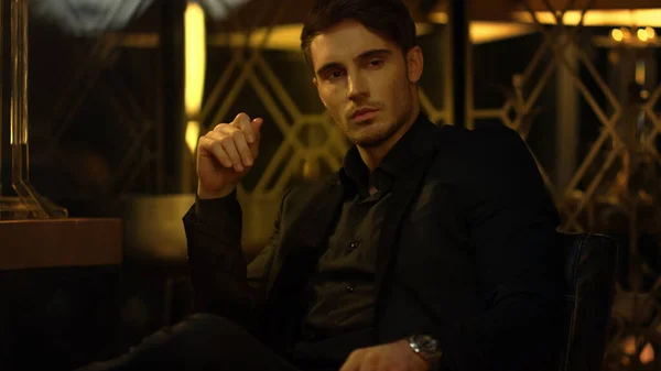 Kendine güvenen bir adam karanlık odada birini düşünüyor. Siyah takım elbiseli patron koltukta oturuyor.