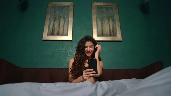 Chica sexy tomando cama de teléfono móvil selfie. Hermosa mujer usando el teléfono en el dormitorio —  Fotos de Stock