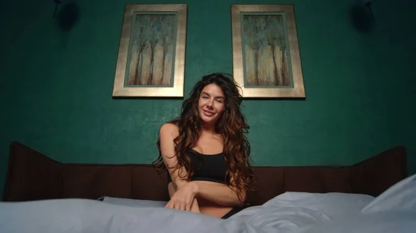 Mulher sorridente posando na cama. Menina sensual jogando cachos no quarto. — Fotografia de Stock