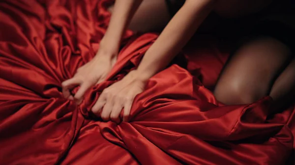 Nainen koskettaa punaista silkkilakanaa sisätiloissa. Hoikka nainen puristamalla satiini kansi. tekijänoikeusvapaita kuvapankkikuvia