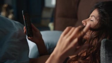 Cep telefonuyla yatakta yatan süslü bir kadın. Parmakları kıvıran seksi kız..