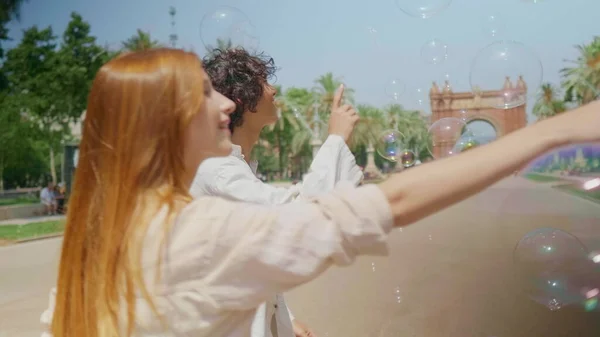 Casal feliz brincando com bolhas. Amigos sorridentes se divertindo com bolhas de sabão — Fotografia de Stock