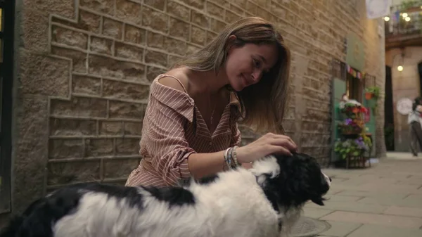 Счастливая женщина гладит собаку на улице в замедленной съемке. Улыбающаяся женщина обнимает собачку — стоковое фото