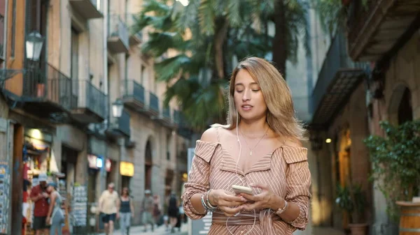 Mulher feliz usando fones de ouvido ao ar livre. Sorrindo menina ouvindo música na rua. — Fotografia de Stock