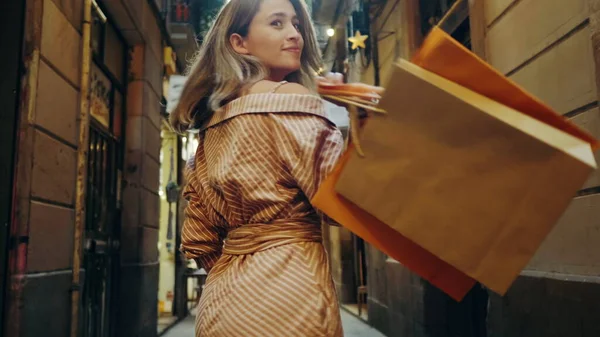 Rückansicht einer einkaufenden Frau, die auf der Straße der Stadt spaziert. Touristenmädchen sucht Kamera — Stockfoto