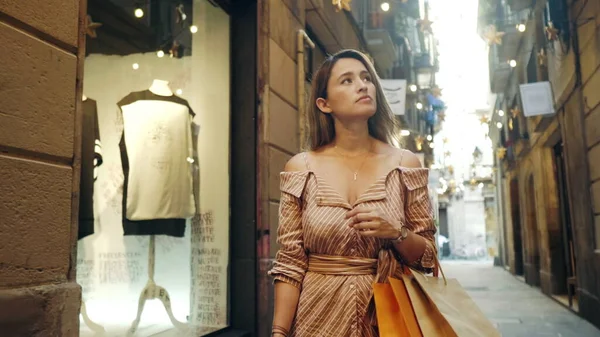 Alışveriş torbalarıyla yürüyen bir turist kadın. Kız vitrinlere bakıyor.. — Stok fotoğraf
