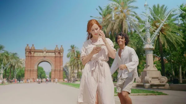 Anıt yakınında cep telefonu arayan odaklanmış bir kadın. Mutlu çift dışarıda sarılıyor.