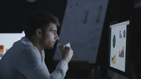 Focused business analyst watching financial graph in night office