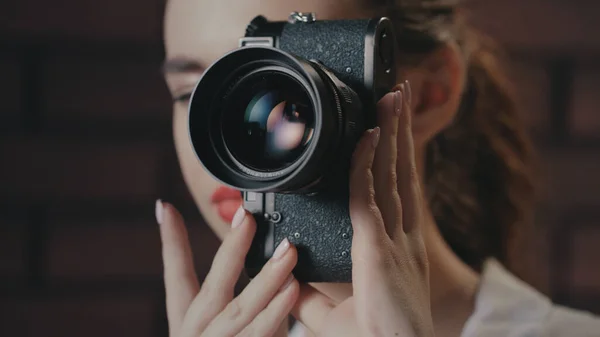 Bella donna scattare foto con fotocamera vintage su sfondo muro di mattoni — Foto Stock