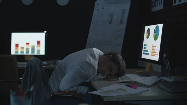 Hombre de negocios cansado durmiendo en la computadora de la mesa de trabajo en la oficina oscura. — Foto de Stock