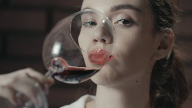 Camdan kırmızı üzüm şarabı içen çekici bir kadın. Kırmızı şarap içen bayan.
