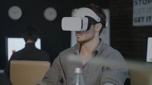 Designer de jogos vestindo fone de ouvido VR e trabalhando em realidade aumentada no escritório — Fotografia de Stock
