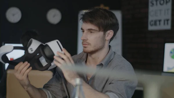 Jovem segurando óculos de realidade virtual no escritório escuro criativo — Fotografia de Stock