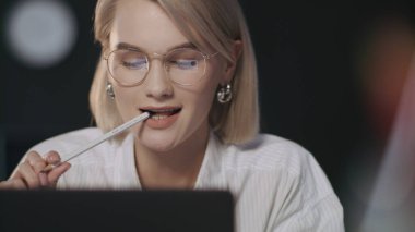 Gece ofisinde bilgisayarın önünde gülümseyen bir iş kadını.