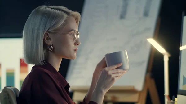 Mulher de negócios concentrada bebendo café computador frontal no escritório da noite — Fotografia de Stock