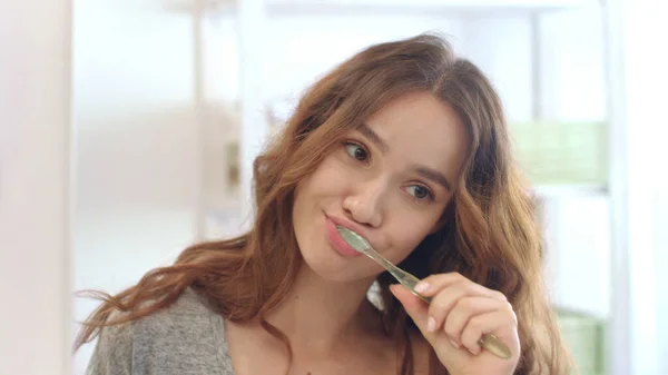 Mujer atractiva usando cepillo de dientes y pasta de dientes para cepillarse los dientes en el baño — Foto de Stock