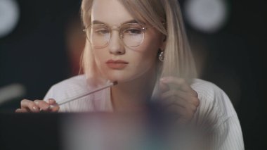 Karanlık ofiste dizüstü bilgisayar arayan dalgın bir iş kadını. İş yerinde çalışan kadın.