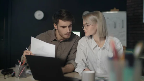 Geschäftspaar arbeitet gemeinsam an Finanzprojekt im dunklen Büro. — Stockfoto