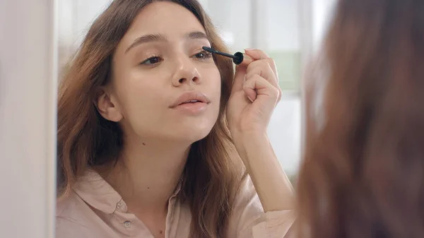 Beautiful woman using mascara for eyelashes front bathroom mirror — Stock Photo, Image