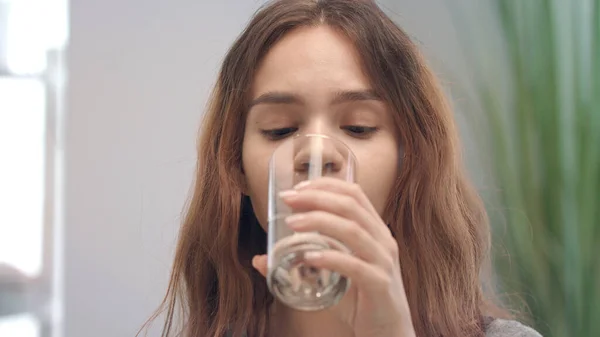 Munter kvinne som tar vitaminkapsler og drikker vann fra glass i baderom – stockfoto