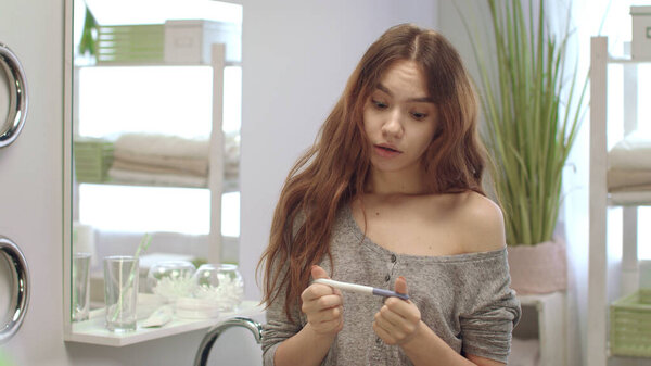 Woman waits pregnancy test results in bathroom. Girl does express ovulation test