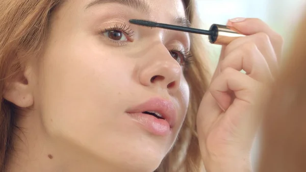 Pretty woman applying black mascara for eyelashes front bathroom mirror — Stock Photo, Image