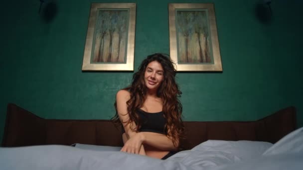 Donna sorridente che posa sul letto. Ragazza sensuale giocare riccioli in camera da letto. — Video Stock
