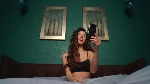 Vrouw met videogesprek mobiele telefoon in bed. naakte meisje holding mobiele telefoon hand. — Stockvideo