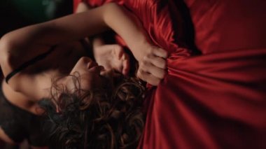 Yatakta saten çarşaf sıkan şehvetli kadın. Yatakta yatan seksi vücut kızı..