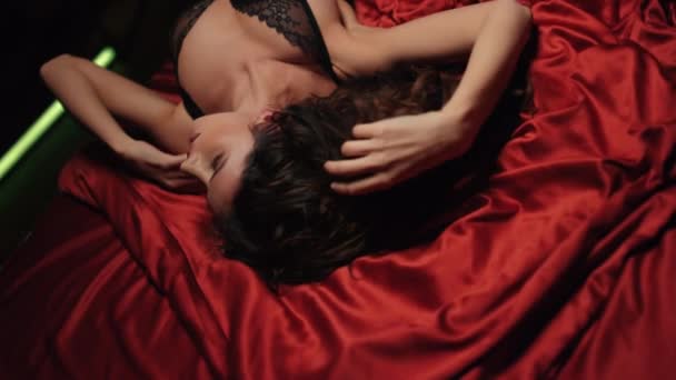 새틴 아마포 침대에서 편히 쉬고 있는 귀여운 소녀. 실크 천으로 만든 카메라를 보고 있는 섹시 한 여자. — 비디오