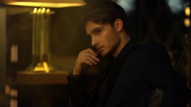 Zeki adam karanlık arka planda düşünceler içinde. Zengin adam koltukta oturuyor.