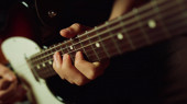 Hudebník hrající na elektrickou kytaru ve studiu. Kytarista štípání akordů rukou