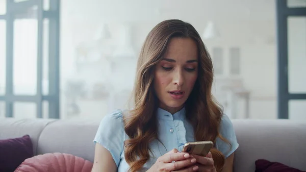 Mujer de negocios leyendo buenas noticias por teléfono en el sofá. Chica charlando por teléfono. —  Fotos de Stock