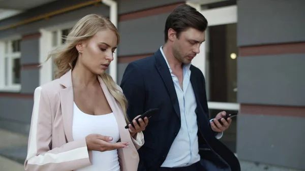 Closeup couple using phones at street. Man and woman texting at beautiful street