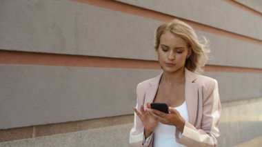Sokakta telefonu kullanan yakın plan bir iş kadını. Sokakta telefonla mesajlaşan kadın.