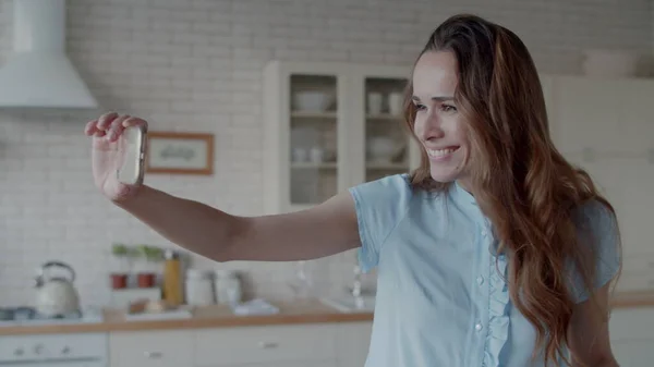 Glada kvinna tar selfie foto i modernt kök. Flicka poserar för foto. — Stockfoto