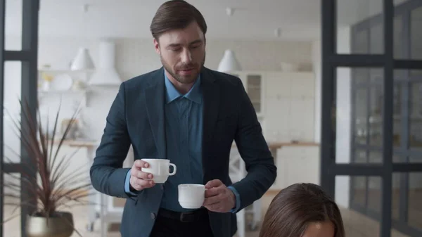 Attraktive Ehemann bringt Teetassen zu seiner Frau nach Hause. Frau im Gespräch mit Mann. — Stockfoto