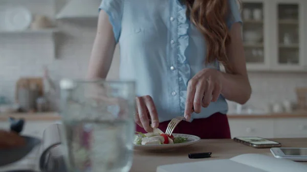 Viehättävä nainen lounastaa nopeasti kotikeittiössä. Nainen syö salaattia. — kuvapankkivalokuva