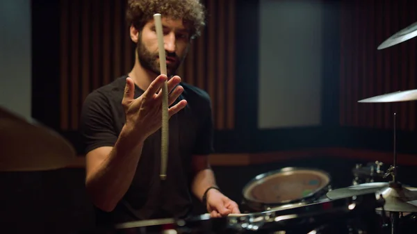 Um músico a rodar uma baqueta no estúdio. Baterista de rock sentado na sala de concertos. — Fotografia de Stock