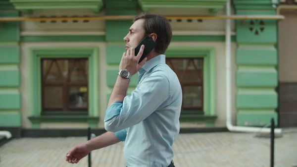 Poważny biznesmen rozmawiający przez telefon na zewnątrz. Biznesmen chodzenie ze smartfonem — Zdjęcie stockowe