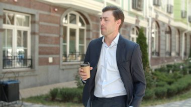 Yakın plan iş adamı kahve içmeye gidiyor. Adam içkiyle işe gidiyor.