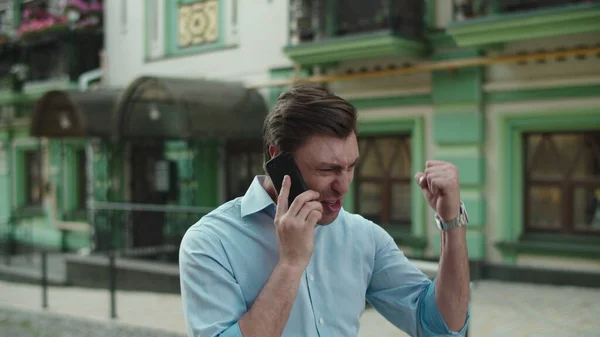 Счастливый бизнесмен празднует победу с мобильного телефона на улице — стоковое фото