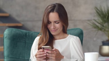 Genç iş kadını akıllı telefondan internette geziniyor. Mutlu kız arayan telefon.