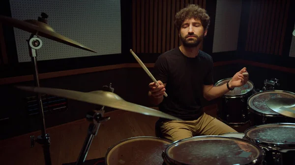 Musician playing rock music in studio. Drummer closing eyes in concert hall.