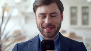 Neşeli iş adamı telefonda internette sörf yapıyor. Telefondaki adam mesaj atıyor..