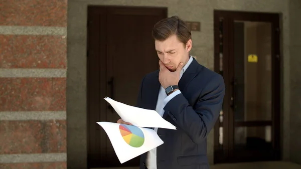 Closeup businessman standing near building. Man standing in suit with documents — Stock Photo, Image