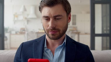 Gülümseyen iş adamı evde telefonla mesajlar okuyor. İnternette sörf yapan adam.