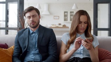 Modern odadaki kanepede oturan genç çift. Yorgun adam kanepede uyuyor.